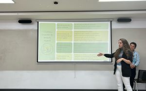 Ana Lucí Pineta pointing at her presentation in the front of a room.