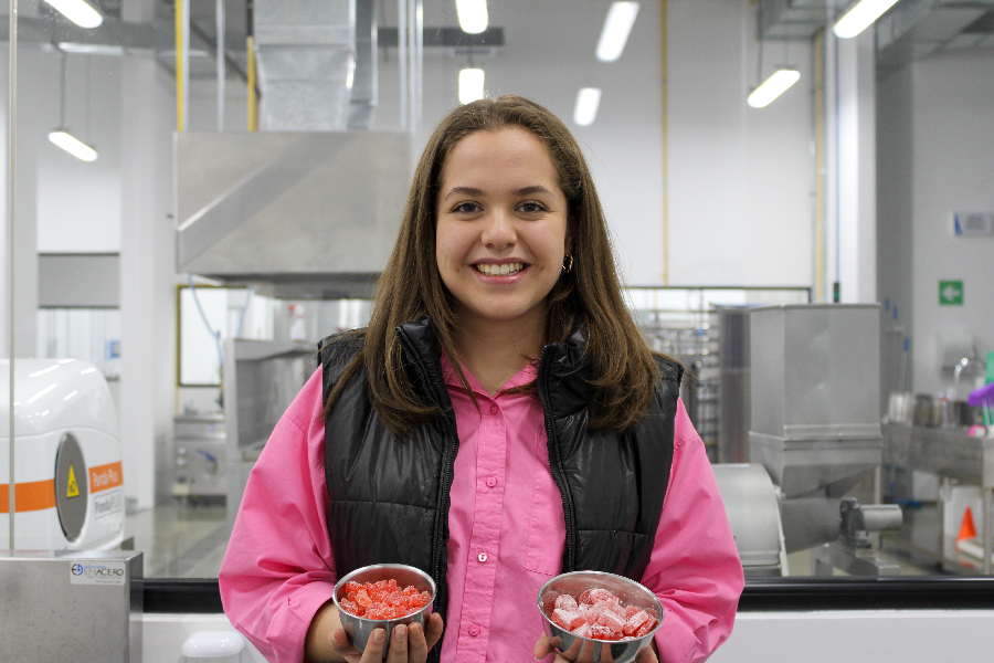 Mujer en laboratorio de alimentos sosteniendo dos prototipos de dulces.
