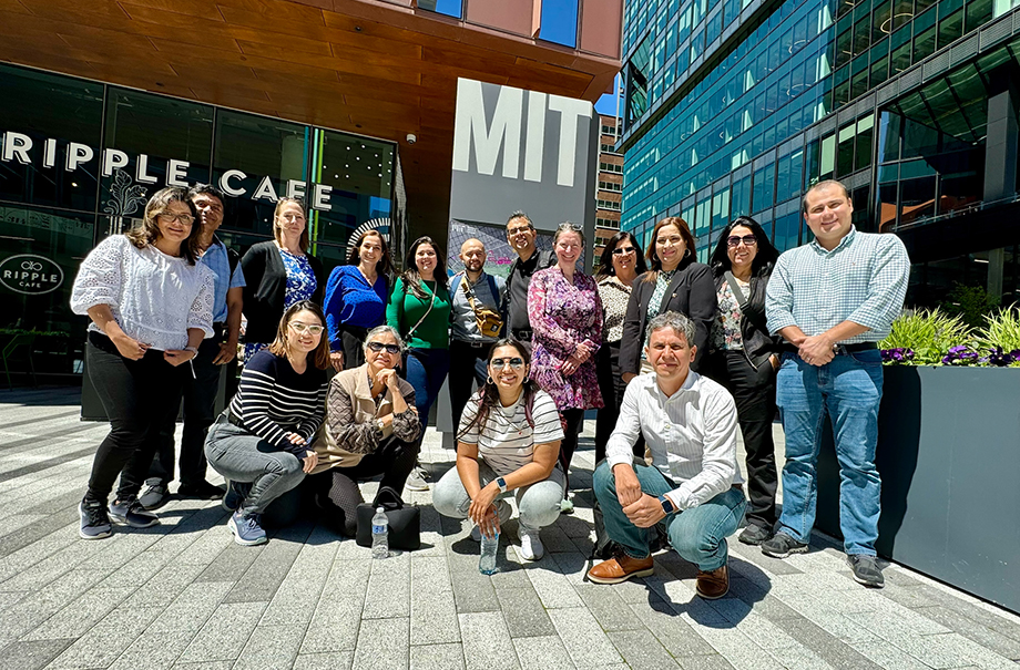 Group of professionals in Kendal Square in front of an MIT sign