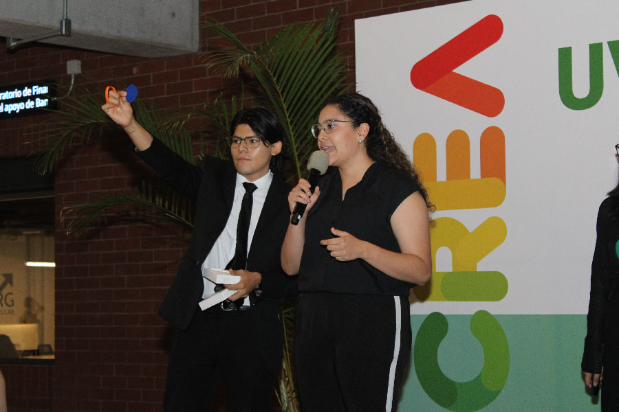 Un hombre y una mujer hablando en un escenario con un micrófono. 