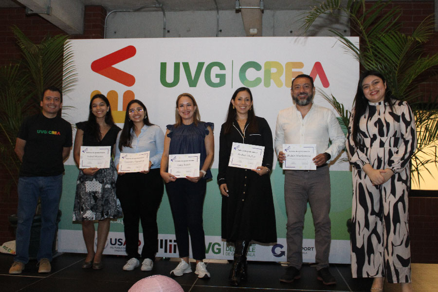 Grupo de personas sobre un escenario con diplomas. 