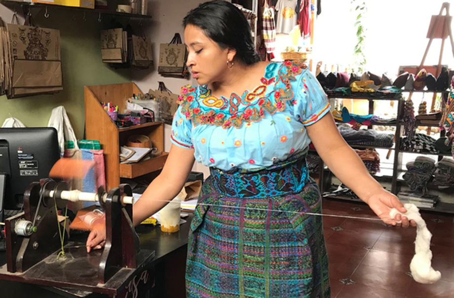 Woman using spinning machine for wool.