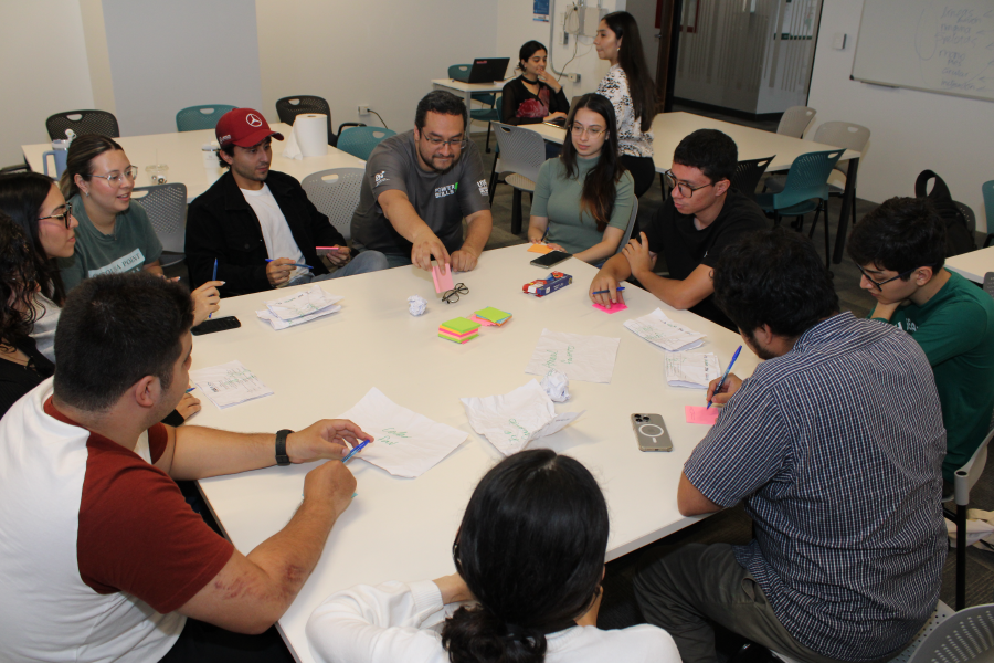 Group of ten students and researchers talking around a table with notes and working papers.