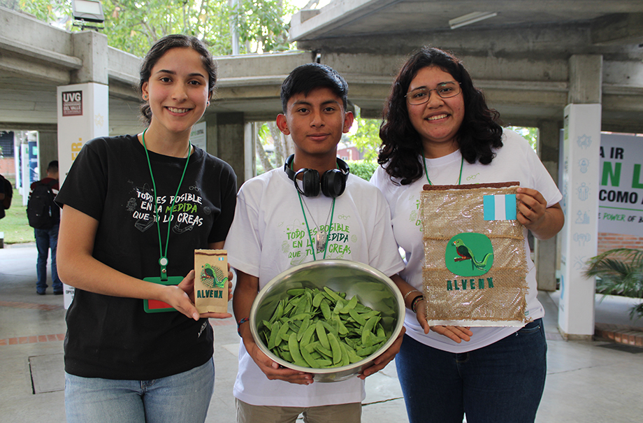 Tres personas sosteniendo distintos artículos hechos a base de arvejas.