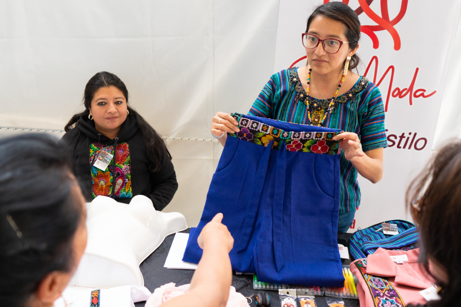 Four women talking, one of them holds a pair of shorts while the other one points towards her.