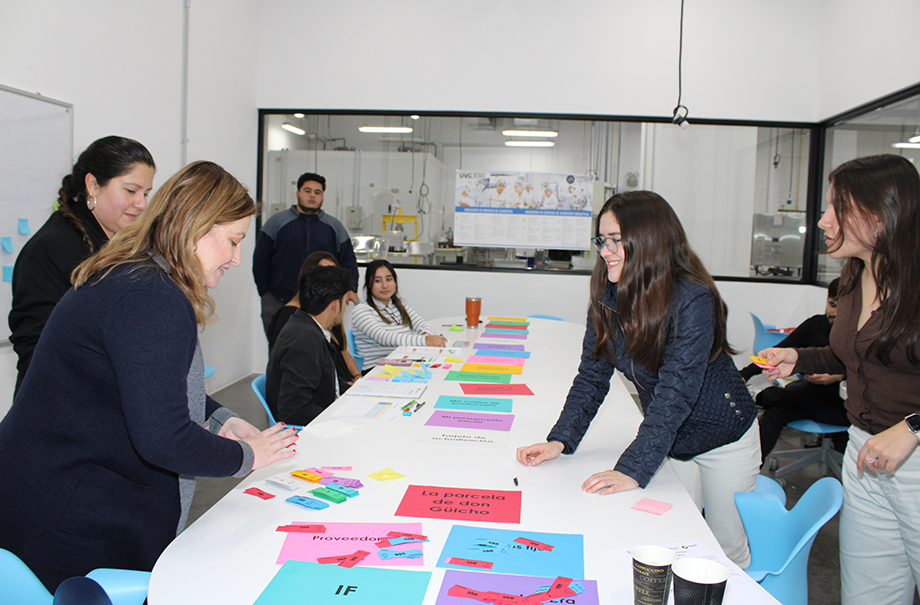 Eight people working around a table with colorful paper spread out and organized.