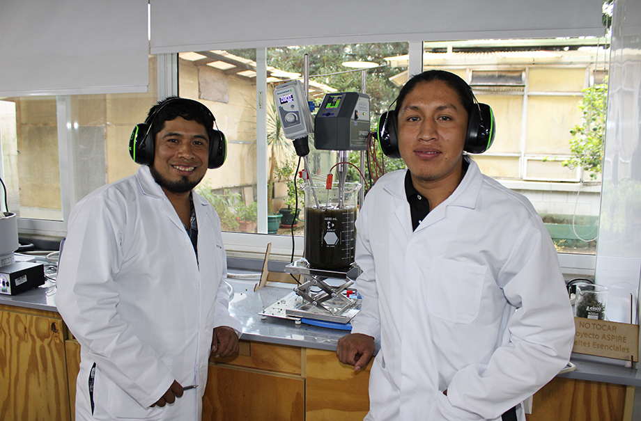 Two men in lab coats working on a piece of lab equipment.