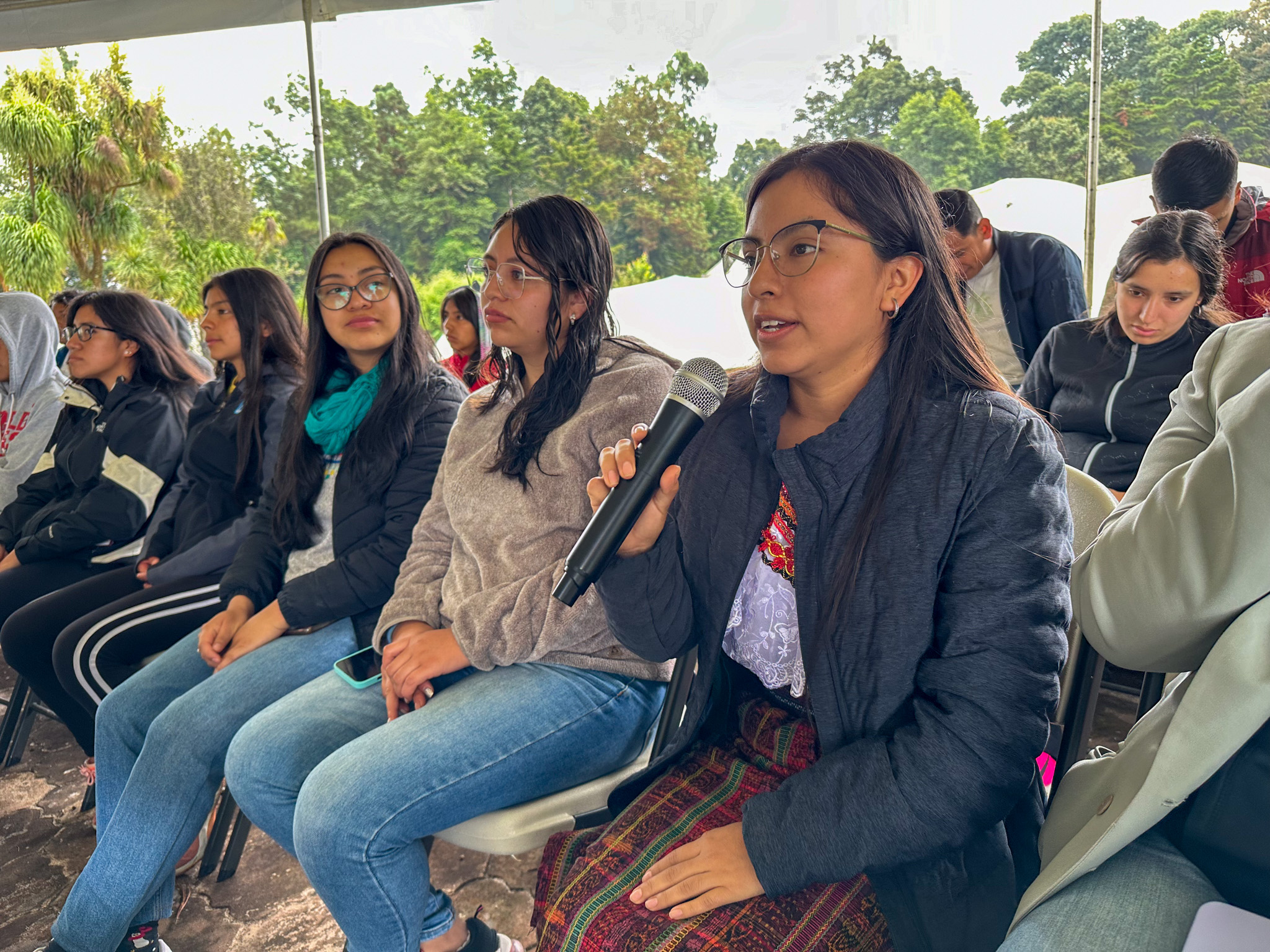 Varias mujeres están sentadas, una de ellas sosteniendo un micrófono.