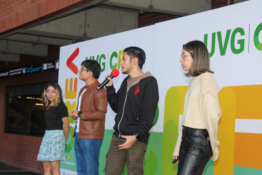 Cuatro personas paradas y uno sosteniendo un micrófono.